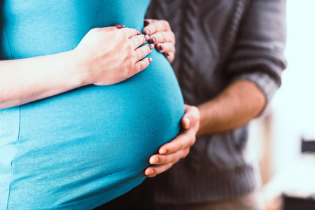 Couple holding hands on pregnant bellyの写真素材