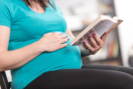 Pregnant woman reading a book at homeの写真素材