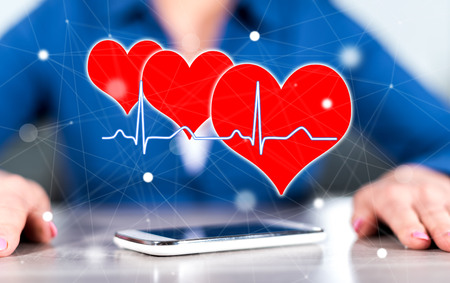 Smartphone with a heart beats graph concept between hands of a woman in background