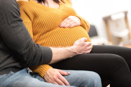Couple holding hands on pregnant bellyの写真素材
