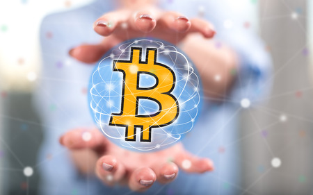 Bitcoin currency concept between hands of a woman in backgroundの写真素材