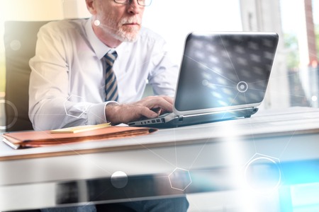 Mature businessman working on laptop in office, light effectの写真素材