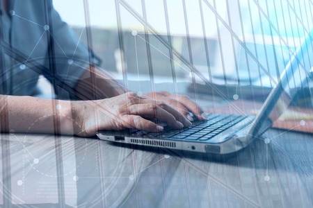 Female hands using a laptop in office, double exposureの写真素材