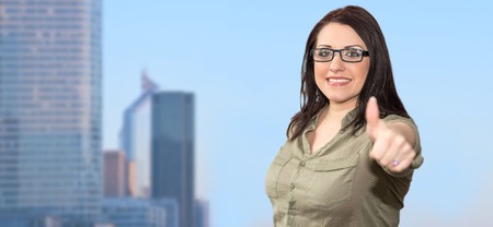Portrait of businesswoman with thumb up on business city backgroundの写真素材