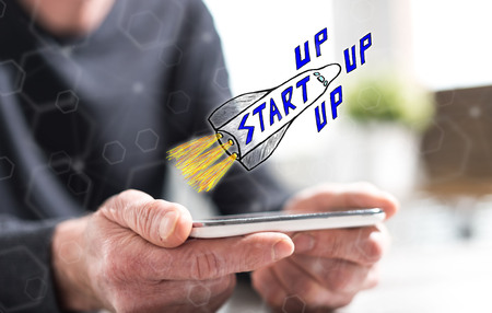 Hands of man holding a smartphone with start up conceptの写真素材