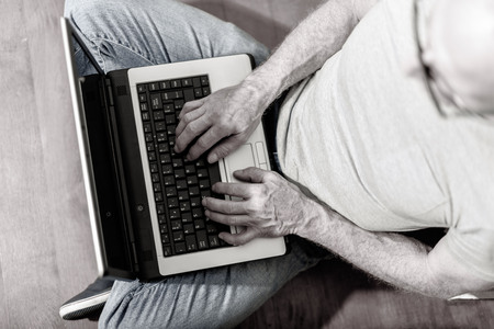 Top view of man sitting on the floor and working on his laptop