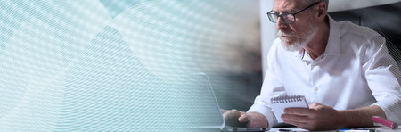 Senior businessman working on laptop in office, light effect, hard light. panoramic banner
