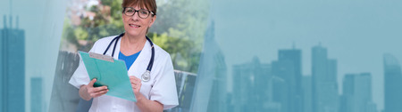 Portrait of female doctor smiling and holding a clipboard. panoramic bannerの写真素材