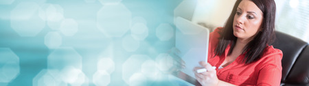 Young attractive businesswoman using a tablet at office, light effect. panoramic bannerの写真素材