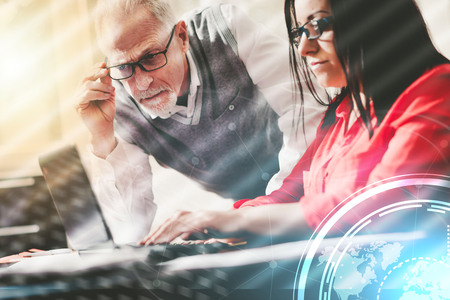 Young businesswoman and senior businessman working together at office, light effectの写真素材