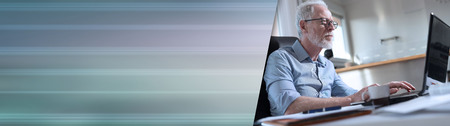 Portrait of senior businessman working on laptop in office, hard light. panoramic bannerの写真素材