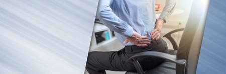 Businessman suffering from back pain in office, light effect. panoramic bannerの写真素材