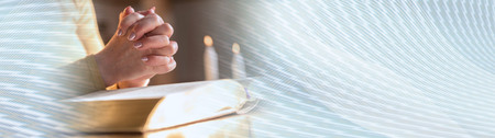 Close up of woman praying with her hands over the bible, hard light. panoramic banner