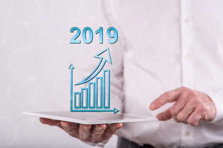 Business growth in 2019 concept above a tablet held by a man in backgroundの写真素材