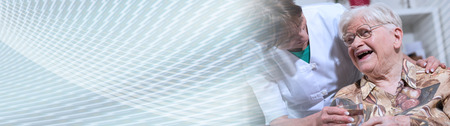 Nurse giving glass of water to happy elderly woman. panoramic bannerの写真素材