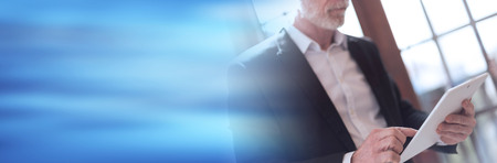 Senior businessman using tablet, hard light effect. panoramic bannerの写真素材