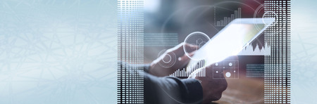 Businessman using his tablet at office, overlayed with graphs. panoramic bannerの写真素材