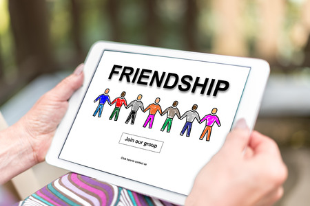 Female hands holding a tablet with friendship conceptの写真素材