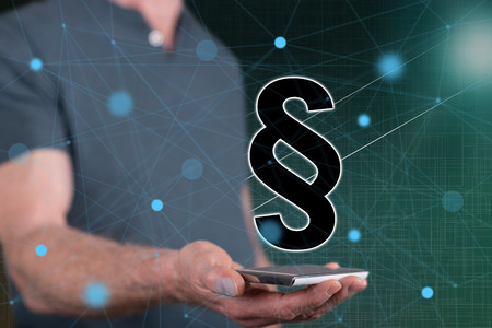 Law concept above a smartphone held by a man in backgroundの写真素材