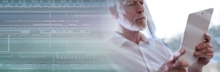 Senior businessman using a digital tablet in office, light effect, hard light. panoramic bannerの写真素材
