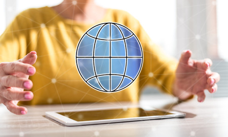 Digital tablet with global business concept between hands of a woman in backgroundの写真素材