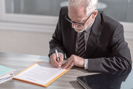 Businessman signing a document in office (Lorem ipsum text used)