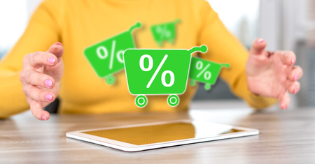 Digital tablet with percent discount concept between hands of a woman in backgroundの写真素材