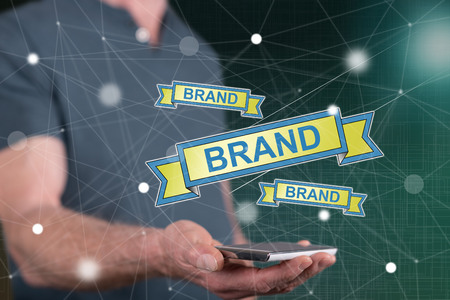 Brand concept above a smartphone held by a man in backgroundの写真素材