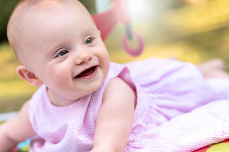 Portrait of cute smiling baby girl outdoors, light effectの写真素材