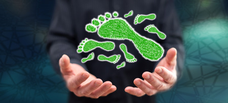 Carbon footprint concept above the hands of a man in backgroundの写真素材