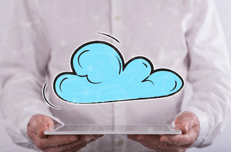 Cloud networking concept above a tablet held by a man in backgroundの写真素材