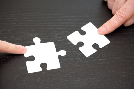 Hands joining two puzzle pieces, teamwork conceptの写真素材