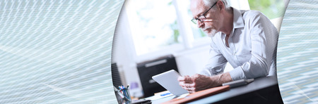 Senior businessman using a digital tablet in office. panoramic bannerの写真素材