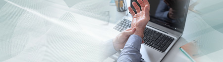 Businessman suffering from wrist pain in office. panoramic banner