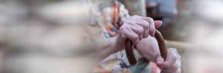 Old woman sitting with her hands on a cane. panoramic bannerの写真素材