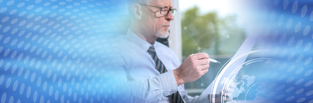 Portrait of mature businessman checking a document in office, overlayed with charts. panoramic bannerの写真素材