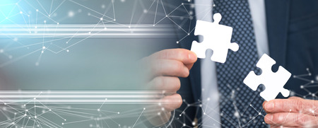 Businessman joining two puzzle pieces, teamwork concept; multiple exposure