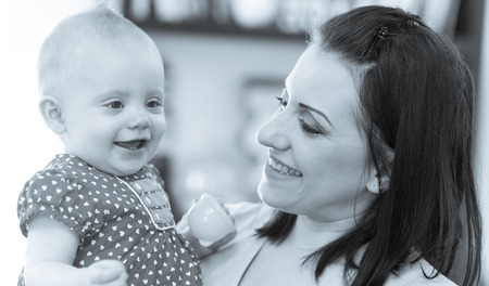 Portrait of happy mother with her cute baby girl at home, black and white