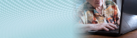 Old woman using a laptop at home. panoramic bannerの写真素材