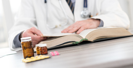 Doctor reading a textbook in medical officeの写真素材