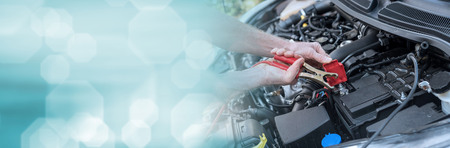Hands of car mechanic using cables to start a car engine. panoramic bannerの写真素材