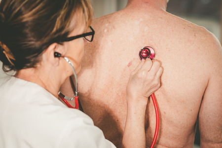 Female doctor using stethoscope to exam patientの写真素材