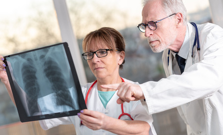Two doctors examining x-ray report in medical office