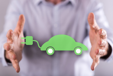 Eco friendly car concept between hands of a man in backgroundの写真素材