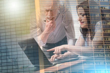 Young businesswoman and senior businessman working together at office, light effect; multiple exposureの写真素材