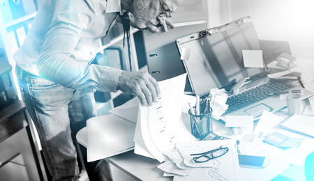 Disorganized businessman looking for documents on his desk, light effect