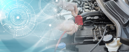 Hands of car mechanic using cables to start a car engine; multiple exposureの写真素材