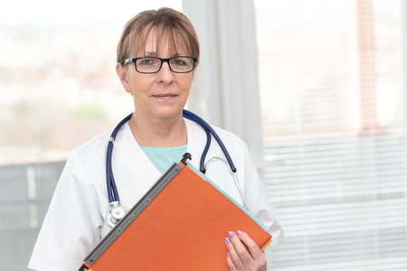 Portrait of female doctor standing and holding a folderの写真素材