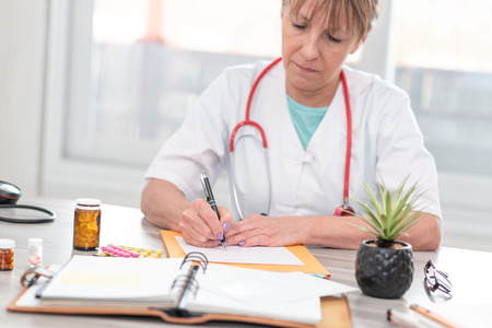 Female doctor writing a medical prescription in officeの写真素材
