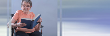 Senior woman sitting and reading a book; panoramic banner